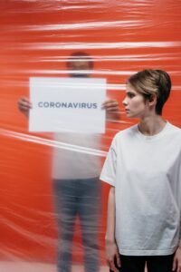 woman with a stressful look at a man holding a poster with coronavirus text