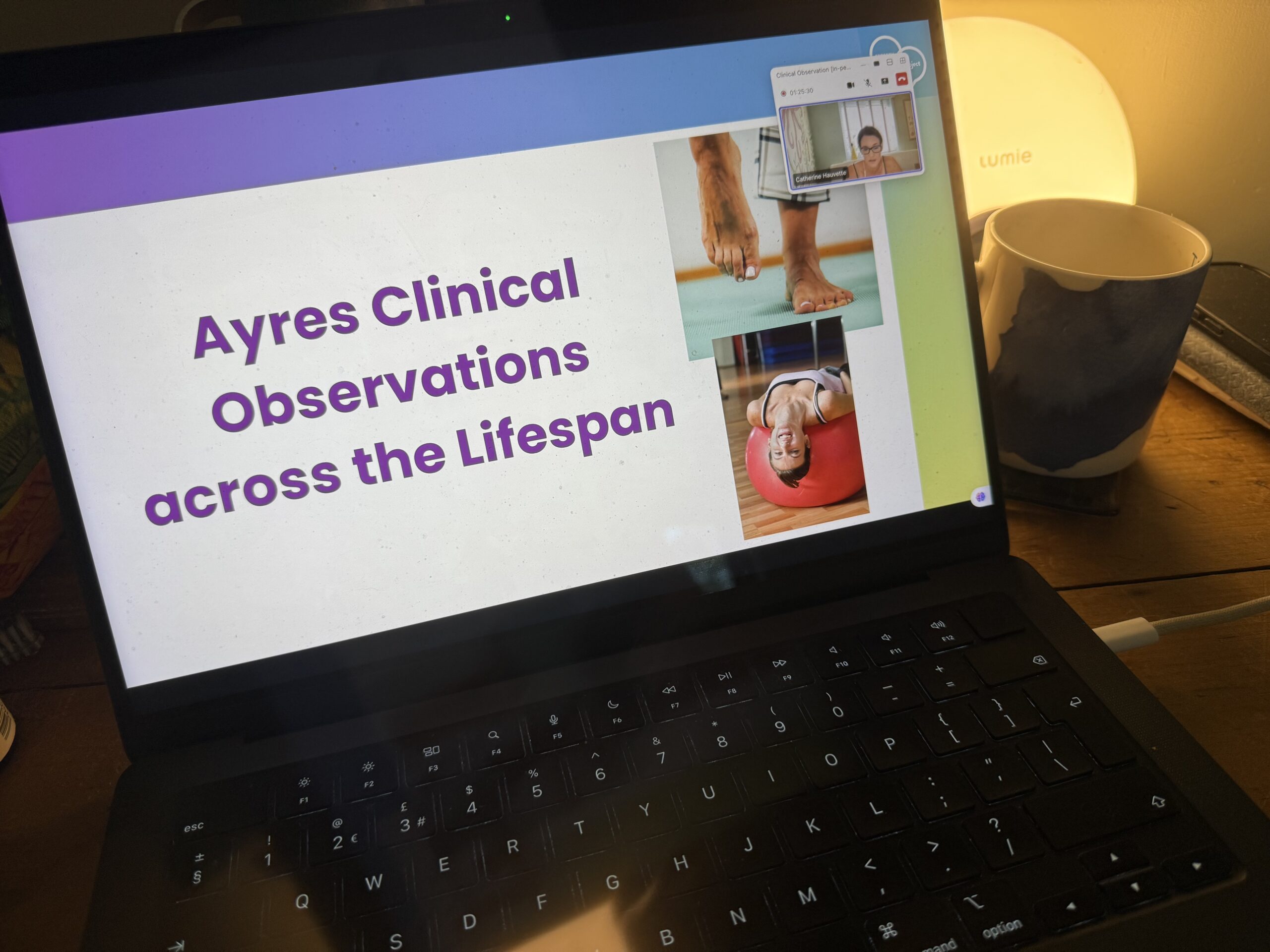 A laptop screen displaying a presentation slide titled Ayres Clinical Observations across the Lifespan in large purple text. The slide includes three photographs: bare feet on a yoga mat, a close-up of feet balancing on tiptoe, and a young woman lying back on a red therapy ball, smiling.